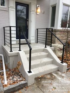 a set of stairs leading up to the front door of a white house with black railings