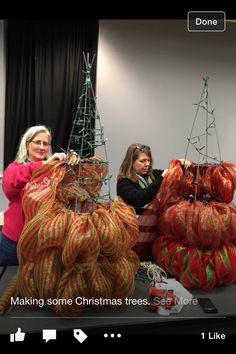 two women are making christmas trees out of bags