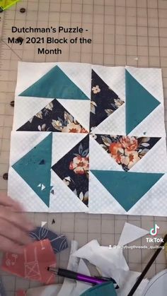 someone is making a quilt on the floor with scissors and paper pieces in front of them