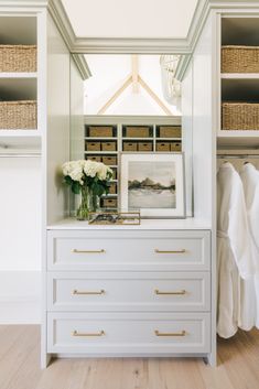 a white dresser topped with lots of drawers under a large mirror next to a closet