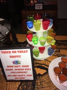 there are many cups on the table with drinks in them and a sign that says trick or treat shots