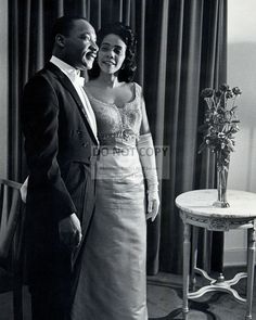 a man and woman standing next to each other in front of a table with flowers