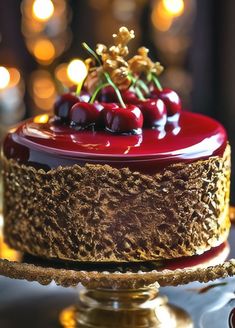 a chocolate cake with cherries on top is sitting on a gold platter and lit candles are in the background