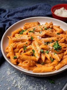 a white bowl filled with pasta covered in sauce and parmesan cheese