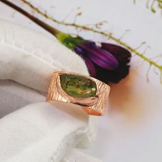 a close up of a ring on a napkin with flowers in the backgroud