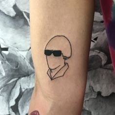 a person with a tattoo on their arm wearing sunglasses and a shirt that has a man's face drawn on it