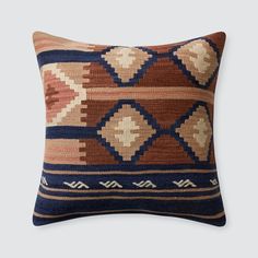 a brown, blue and tan pillow on a gray background