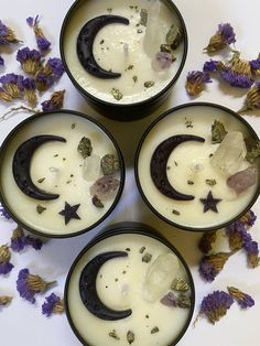 four black bowls filled with different types of moon and stars in front of purple flowers