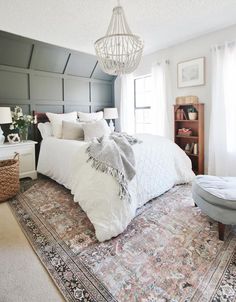 a bedroom with a large rug and a chandelier hanging from the ceiling above it