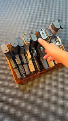 a hand is pointing at an assortment of electronic devices in a display case on a table