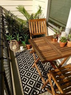 a table and chairs on a small balcony with potted plants in the window sill