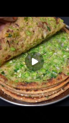 a stack of flatbreads with broccoli and cheese on top is being held by a person