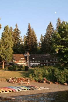 there are many canoes lined up on the shore in front of a large house