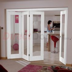 a woman is standing in the kitchen looking through french doors