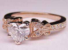 an engagement ring with a heart shaped diamond in the center and two smaller hearts on each side