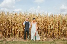 a bride and groom standing in front of a corn field