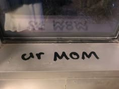 the word'mom'is written in black ink on a metal surface next to a window