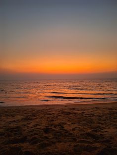 the sun is setting over the ocean with waves coming in from the shore and sand on the beach