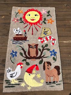 a rug with animals, birds and flowers on it sitting on a wooden floor next to a wall