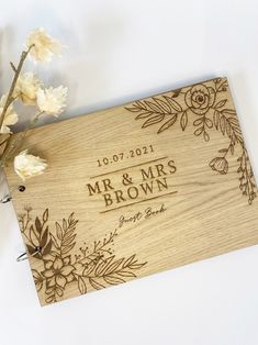 a personalized wooden wedding guest book with flowers on the front and back cover is shown