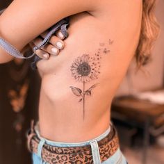 a woman's stomach with a flower tattoo on it