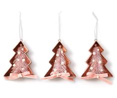 three christmas tree ornaments hanging from strings on white background, with pink ribbon and beading