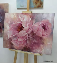 three paintings on easels with one being painted