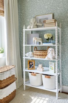 a white shelf with baskets and stuffed animals on it in front of a blue wall