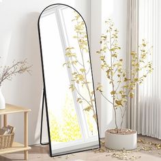 a large mirror sitting on top of a wooden floor next to a vase filled with flowers