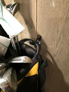 a golf club in a bag next to a wooden wall with other items on it