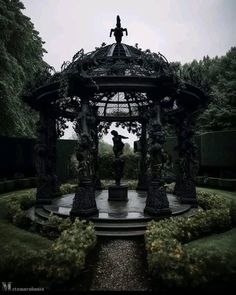 a gazebo in the middle of a park with statues on it's sides