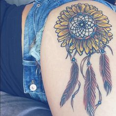 a woman's thigh with a sunflower and dream catcher tattoo on the side