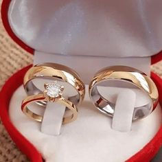 two gold wedding rings in a red velvet box with a white diamond on the top