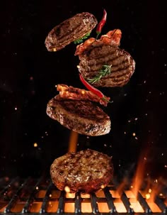 hamburgers being grilled on the grill with hot sauce and ketchup flying through the air