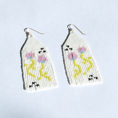 two pairs of beaded earrings with white and yellow designs on the front, one is shaped