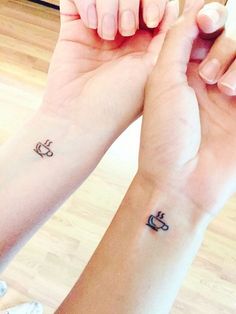 two people holding hands with tattoos on their wrist and one has a coffee cup in the middle