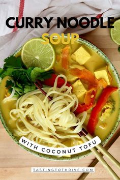 a bowl of curry noodle soup with chopsticks and lime slices on the side