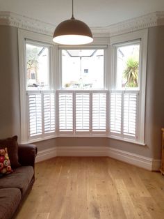 an empty living room with wooden floors and white shutters on the window sill