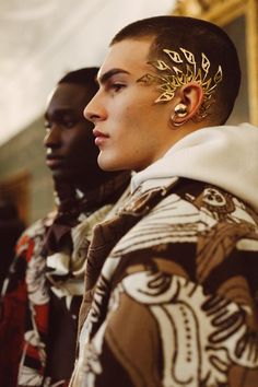 two men with gold ear piercings on their ears and one wearing a patterned jacket