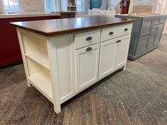 a kitchen island sitting in the middle of a room next to other cabinets and drawers