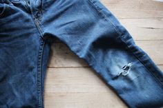 a pair of blue jeans that have been ripped and are sitting on a wooden floor