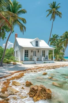 a white house sitting on top of a sandy beach next to the ocean with palm trees