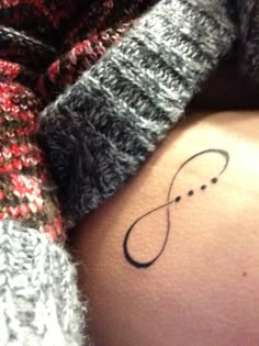 a woman's stomach with a tattoo on the side of her belly and an infinite symbol