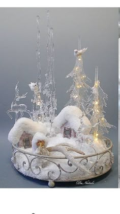 a white christmas tree with lights and snow on it's base, next to an image of a miniature sleigh in the shape of a snowy village