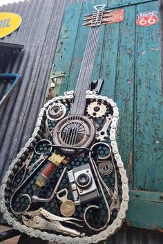 a guitar made out of old parts is sitting on the side of a blue building