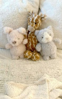 four stuffed animals sitting on top of a bed