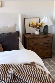 a bedroom with a bed, nightstand and flowers on the night stand next to it