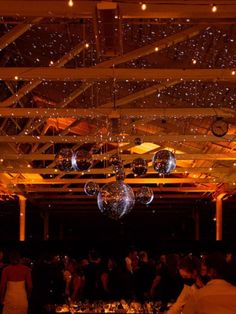 a large room filled with lots of people and disco ball decorations hanging from the ceiling