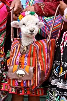 two women carrying colorful bags with a sheep in the middle one is holding a purse