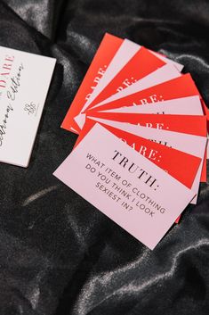 some red and white business cards are laying on a black cloth, with the words true truth written in cursive writing